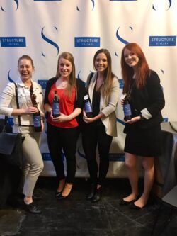 Amanda Sellsted posing with colleagues holding branded bottles at an event during her time at her second professional position